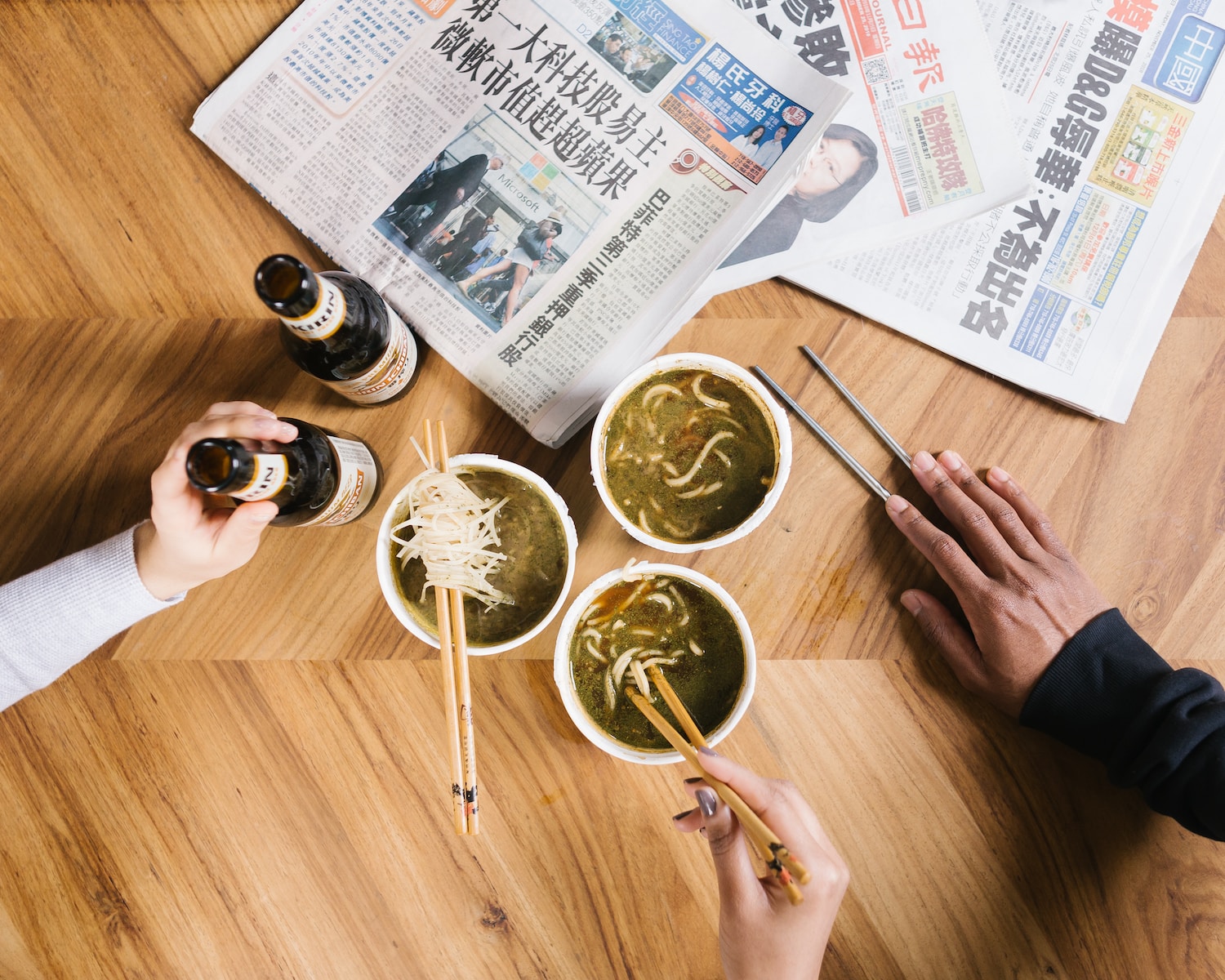 three cup of noodles on table beside newspaper